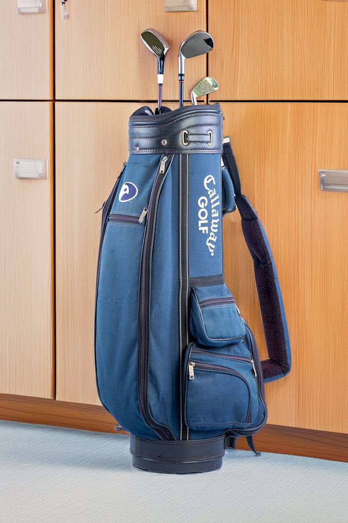 Blue golf bag with clubs in an indoor locker room, ideal for sports enthusiasts.
