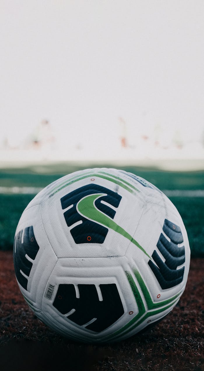 Detailed close-up of a soccer ball on a grassy field in daylight.